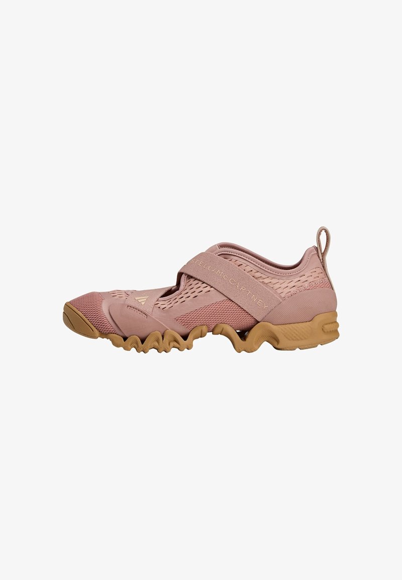 Light pink athletic shoe with a textured mesh upper, elastic strap, and a flexible rubber sole featuring a wavy design.