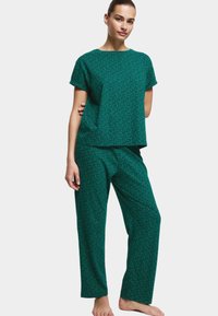 Zielony komplet piżamowy w wzory, składający się z bluzki z krótkim rękawem i luźnych spodni, wykonany z miękkiego materiału, w kolorowe kropki.