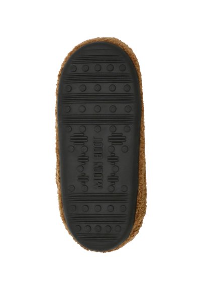 Semelle en caoutchouc noir avec des crampons circulaires et un logo, fixée à une tige de chausson marron duveteuse, vue du dessous.