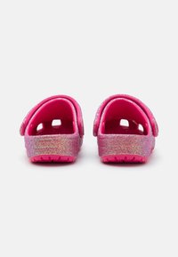 Zoccoli glitter rosa con finitura lucida, dotati di schiena aperta, fori di ventilazione e suole testurizzate per garantire grip.