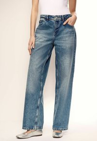 Jeans de mezclilla de tiro alto en un tono azul claro y de corte ancho, con una textura deslavada, diseño de cinco bolsillos y una costura sutil en contraste.