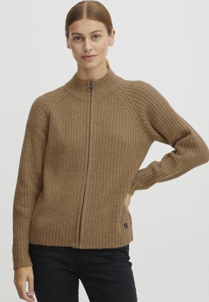 Brown ribbed knit sweater with a high neckline, full zipper, and side pockets. Features textured fabric and a small accent near the hem.