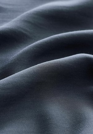 Tela azul marino oscuro con una textura suave y lisa, y un brillo sutil, que exhibe suaves ondulaciones y pliegues a lo largo del material.