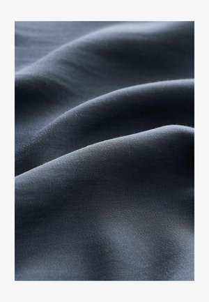 Donker marineblauwe stof met een gladde, zachte textuur en subtiele glans, die zachte golven en plooien door het materiaal heen weergeeft.