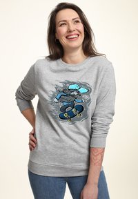 Felpa grigia con una grafica colorata di uno skateboarder sul davanti. Il tessuto sembra morbido, con polsini e orlo a costine.