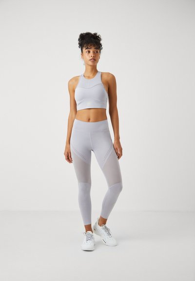 Lichtgrijze sportset met een cropped sportbeha met een textuurpatroon en hoge leggings met mesh-inzetten en subtiele accenten.