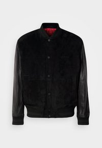 Black bomber jacket with suede body and leather sleeves, ribbed cuffs and hem, snap button closure, and red interior lining.