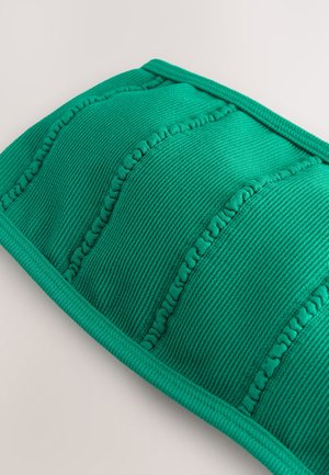 Zöld bordázott textil párna steppelt részekkel, texturált varrással és sima, lekerekített éllel. Puha anyagú kivitel.