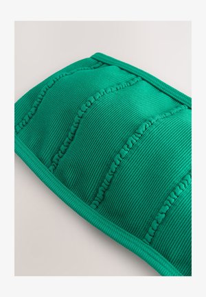 Zöld bordázott textil párna steppelt részekkel, texturált varrással és sima, lekerekített éllel. Puha anyagú kivitel.