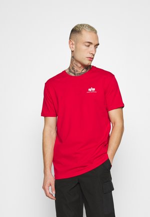 Rotes Baumwoll-T-Shirt mit Rundhalsausschnitt und kurzen Ärmeln. Mit einem weißen Logo auf der Brust und einer lockeren Passform, präsentiert vor einem neutralen Hintergrund.