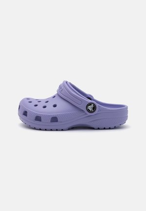 Lilla slip-on træsko med ventilationshuller, tekstureret sål og justerbar hælstrop med rundt logo.