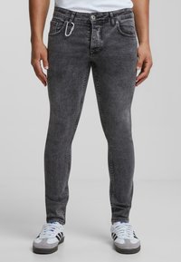 Szürke farmernadrág, slim fit szabással, öt zsebbe, gombos derekú, és elöl karabiner klipszel a részletek fokozása érdekében.