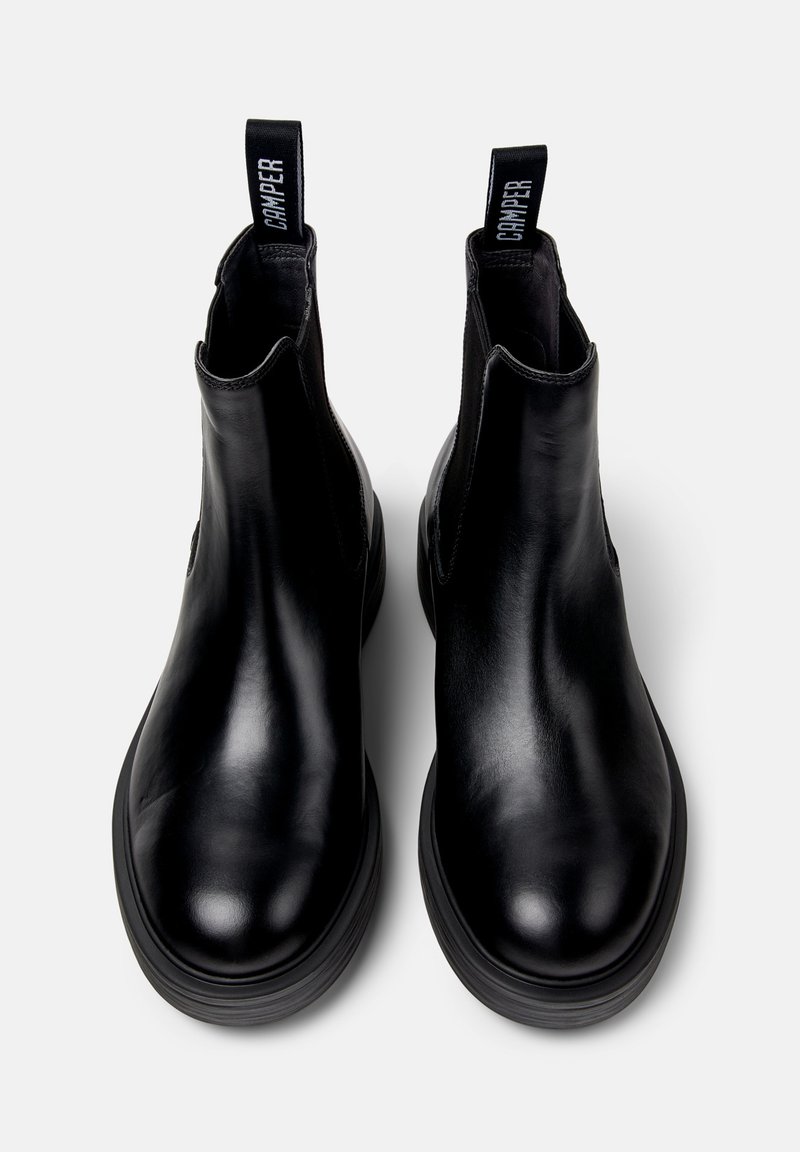 Pair of black leather Chelsea boots with thick soles and pull tabs labeled "Camper," shown from top view on white background.