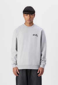 Gray sweatshirt with long sleeves, round neckline, and ribbed cuffs. Features a black logo on the left chest. Made from soft material.