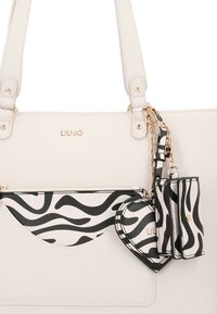 Borsa sintetica bianca con finiture in oro. Presenta una tasca con stampa zebra bianca e nera e accessori coordinati attaccati da una catena.