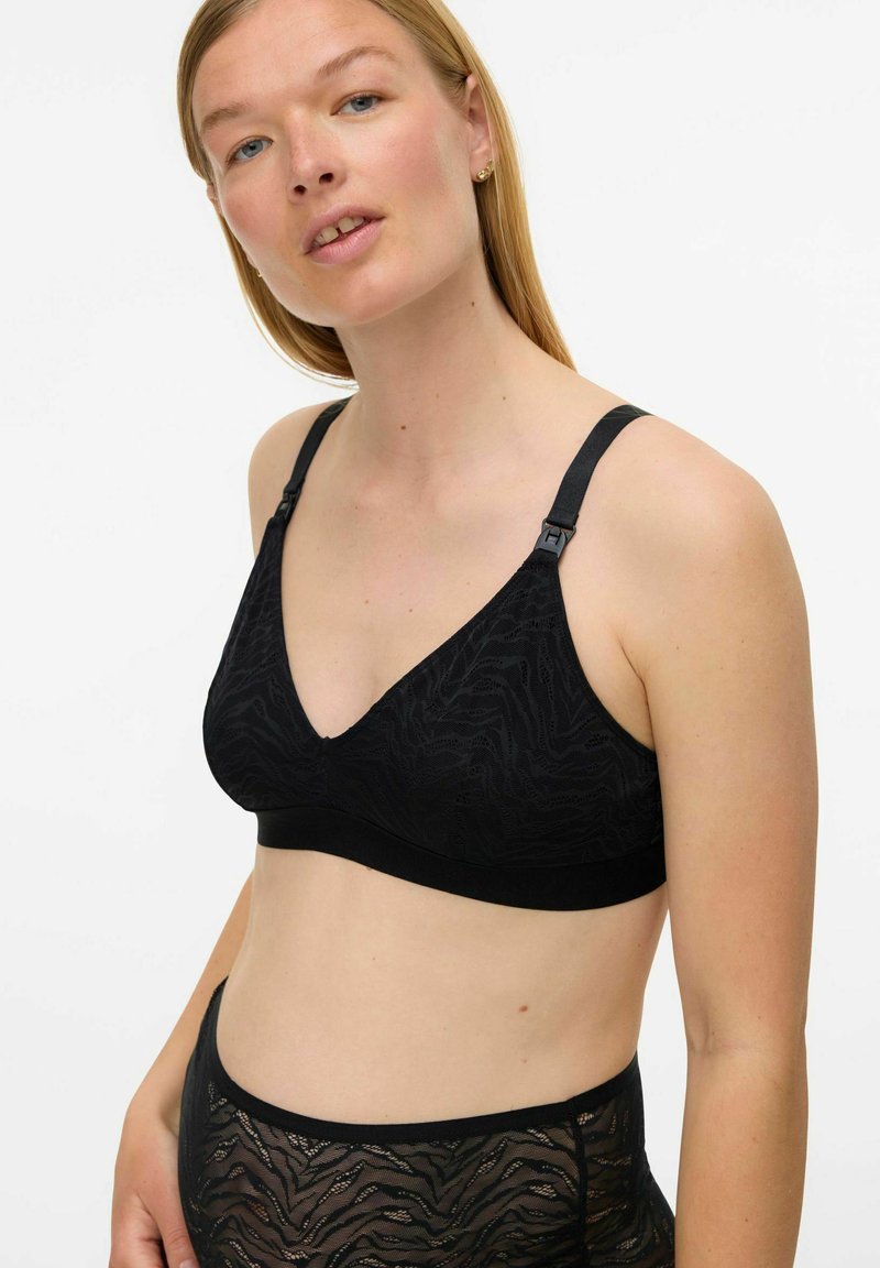 Melns mežģīņu bralets ar V veida izgriezumu, regulējamām siksnām un strukturētu rakstu. Gluds melns apakšmala papildu atbalstam.