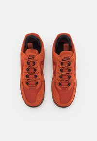 Paire de baskets Nike Air rouge-orange avec des accents noirs, en mesh et daim, vue de dessus sur un fond blanc.