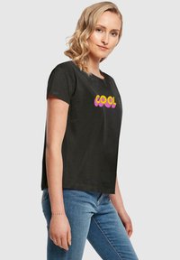 Sort bomulds t-shirt med teksten "COOL" i en gradient af pink og gul. Kortærmet og med en afslappet pasform.