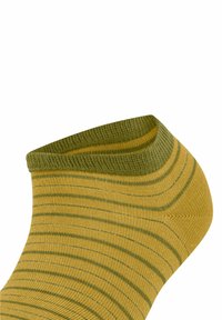 Gelbgestreifte Socke mit einem grünen gerippten Bündchen, weichem Strickmaterial und einer sich verjüngenden Form an der Zehe.