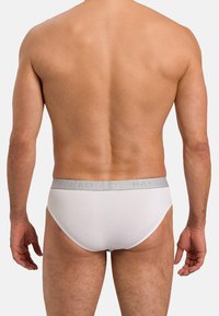 Slip di cotone bianco con fascia in logo grigia, caratterizzato da una vestibilità aderente e fianchi senza cuciture per il massimo comfort, mostrato dalla parte posteriore.