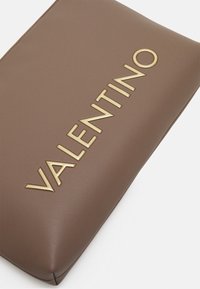 Clutch in pelle marrone con texture liscia e logo "VALENTINO" in oro impresso sulla parte frontale. Formato rettangolare compatto con chiusura a zip.