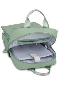 Zöld hátizsák sima textúrával, cipzáros záródással és dupla fogantyúval. A belső rész egy szürke rekeszt tartalmaz, biztonsági pánttal.