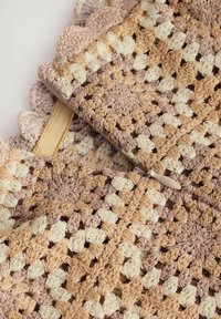 Sacchetto all'uncinetto con blocchi di colore beige e crema neutri, caratterizzato da un bordo ondulato e una chiusura a zip con una linguetta beige. Tessuto testurizzato.