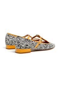 Zapatos planos con estampado de cebra, exterior en blanco y negro con acentos amarillos. Presentan un tacón bajo y un diseño de tiras cruzadas.