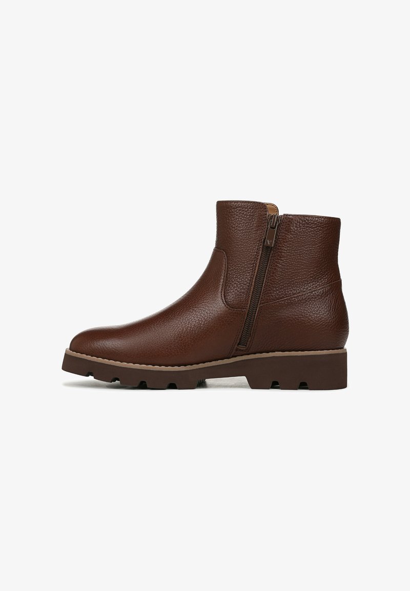 Brown leather ankle boot featuring a textured finish, side zipper, and a sturdy, lug sole for traction. Minimalist design with a rounded toe.