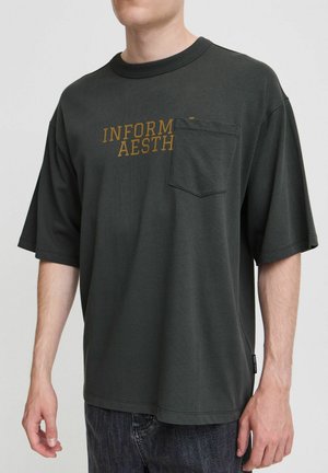 Dark green oversized t-shirt made of cotton with short sleeves, featuring a chest pocket and "INFORMAL AESTHETIC" text printed in gold.