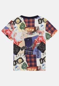 T-shirt à manches courtes avec un design en patchwork, affichant des motifs colorés, des graphismes d'ours et diverses textures textiles. Col bleu marine.