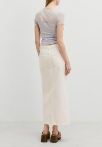 Lichtgrijs mesh T-shirt met korte mouwen, gecombineerd met een witte lange denimrok en bruine chunky hakken. Achteraanzicht weergegeven.