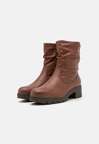 Botas de piel marrón hasta el tobillo con un diseño arrugado, puntera redondeada y suela gruesa con un dibujo en el tread.