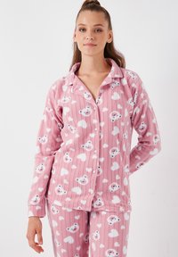 Set de pijama roz dintr-un material moale, cu textură în dungi, având un model cu fețe de urși zâmbitori și inimioare, cu bluză cu nasturi și pantaloni asortați.