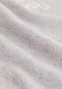 Mäkká, svetlosivá pletenina so záberom zblízka ukazujúcim jemné, rovnomerné stehy a jemné textúrne detaily.