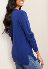 Maglione leggero blu con texture a costine e spacchi laterali. Maniche lunghe e collo rotondo, abbinato a jeans in denim chiaro.