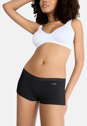 Zwarte shorts met kantafwerking, gecombineerd met een witte beha. De stof is glad en rekbaar, ontworpen voor comfort. Bevat het merklogo op de shorts.