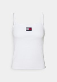 White ribbed tank top with thin straps. Features a black, red, and white rectangular logo patch that reads "TOMMY JEANS" centered on the chest.