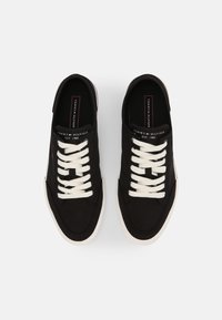 Schwarze Leinensneaker mit weißen Schnürsenkeln, Gummisohlen und einem Logoetikett auf der Zunge. Abgerundete Spitze, flaches Design.