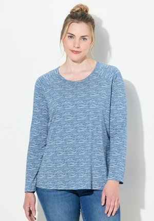 Maglia a maniche lunghe blu con motivo a onde. Realizzata in materiale morbido, ha un collo rotondo e una vestibilità comoda. Abbinata a jeans di denim.