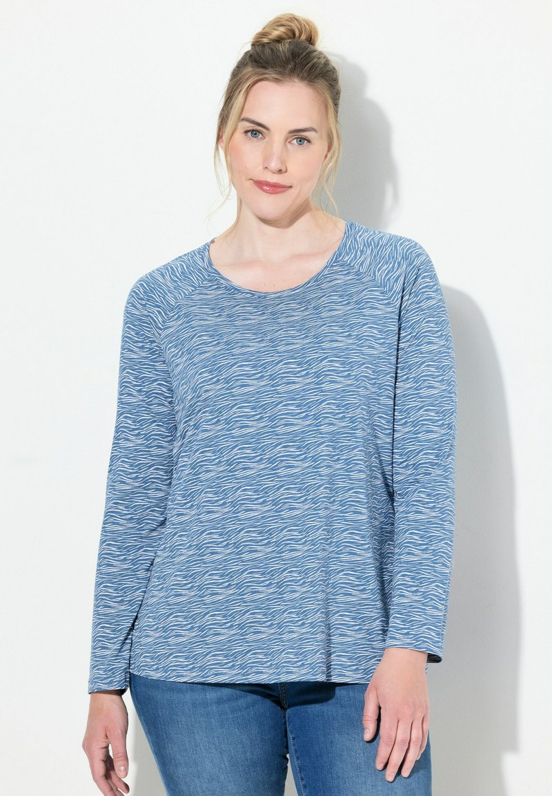 Top azul de manga larga con un patrón de olas. Fabricado en material suave, con un cuello redondo y un corte relajado. Combina con jeans de denim.