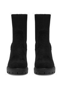 Fekete bokacsizma sima velúrból készült felsőrésszel és bordázott szövetbetéttel. Tartós fekete gumitalppal rendelkezik, amelynek barázdás mintázata van.