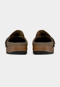 Ζευγάρι καφέ σουέντ σανδάλια χωρίς λουράκια με παχιά σόλα από φελλό και μαύρη λαστιχένια εξωτερική σόλα, σε εικόνα από πίσω με φόντο λευκό.