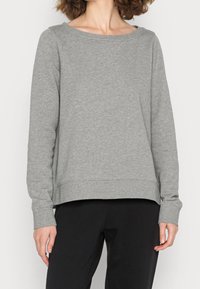 Sudadera gris con un escote amplio, mangas largas y un ajuste relajado. Tejido suave con textura, puños acanalados y un dobladillo ligeramente corto.