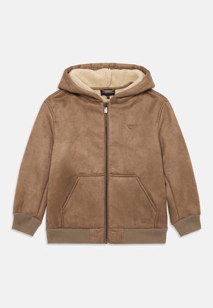 Barna zipzáras kapucnis pulóver puha, plüss belső résszel, elülső zsebekkel és bordázott mandzsettákkal. A mellkasán logó hímzéssel és kapucnival rendelkezik.