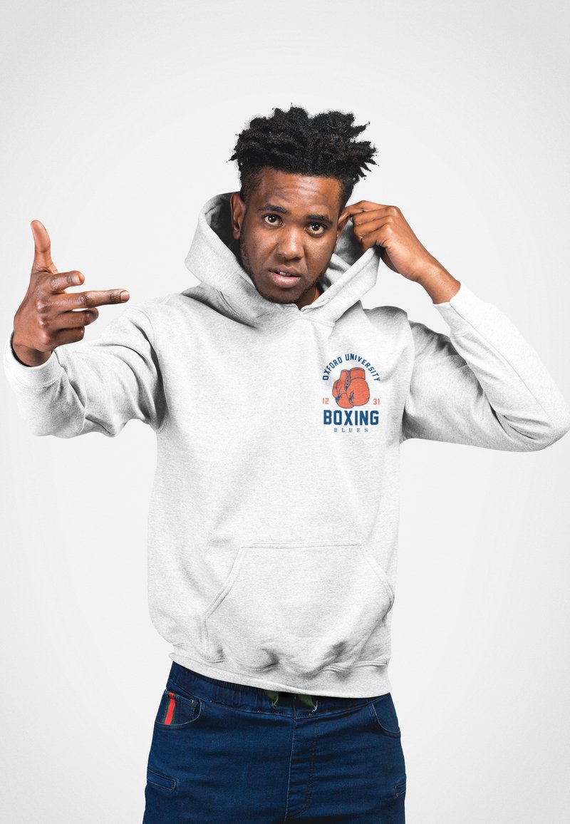 Grå hoodie med en framficka, prydd med en boxningsgrafik och textdesign i blått och orange. Bärs av en person med kort hår.