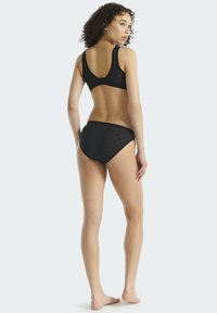 Czarny komplet bikini z wzorzystym topem typu bralette i dopasowanymi dołami. Materiał ma gładką teksturę i prosty, minimalistyczny design.