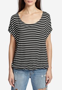 Camiseta de rayas blancas y negras con escote en forma de barco y mangas cortas, hecha de una tela suave, combinada con jeans ligeros de mezclilla desgastados.
