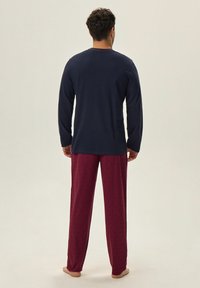 Granatowa koszula bawełniana z długim rękawem w połączeniu z bordowymi spodniami pijamowymi z delikatnym wzorem. Prosty, luźny krój o klasycznym fasonie.