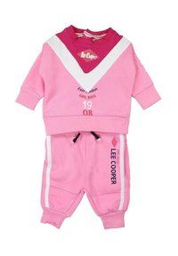 Ensemble de surv êtement rose avec un sweat à bloques de couleurs comportant un design en chevrons blancs et une impression graphique, associé à un jogging assorti.